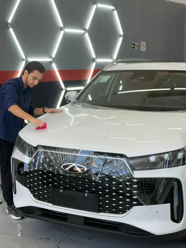 Profissional aplicando PPF na frontal de SUV branco